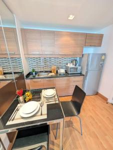 a kitchen with a table and a refrigerator at Cozy, Spacious 2-Bedder with City, Park View, Near Nana BTS in Bangkok