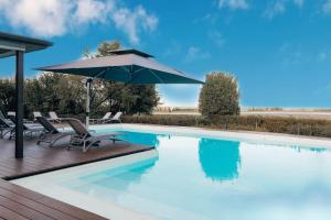 a swimming pool with chairs and an umbrella at Tuscany Garden Inn - Boutique B&B in Castel San Pietro Terme