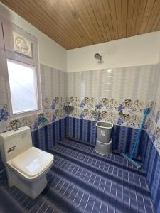 a blue tiled bathroom with a toilet and a window at Kath Kuni Cafe & Stay Shangarh in Shangarh +33 photos