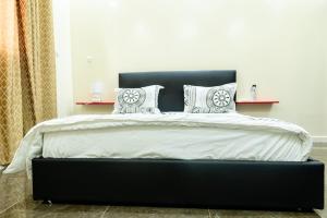 a bedroom with a black bed with white sheets and pillows at Appartement Somone , Sall Residence in Mbour