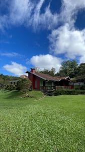 a red house with a green field in front of it at Cantinho da Cerejeira in Santo Antônio do Pinhal