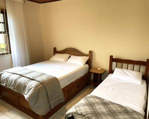 a bedroom with two beds and a window at Cantinho da Cerejeira in Santo Antônio do Pinhal