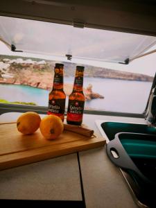 two bottles of beer sitting on a cutting board with oranges at Menorca van life in Ciutadella
