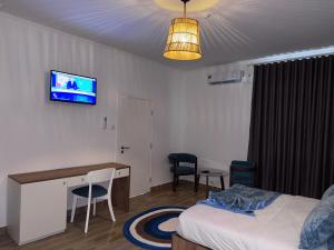 a room with a bed and a desk and a tv at Oceano Boutique Hotel in Lobito