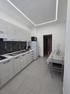 eine Küche mit weißen Schränken und einem Tisch darin in der Unterkunft Casa Vacanze San Marco in Castellammare di Stabia