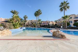 a swimming pool at a resort with palm trees at H&O Limnaria Elegance Pool View Apartment in Paphos City