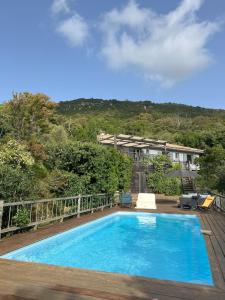 a large blue swimming pool on a wooden deck at Punta di l'Ortu House in Conca