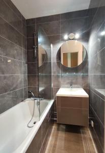 ein Badezimmer mit Badewanne, Waschbecken und Spiegel in der Unterkunft Hesperie studio in Chamalières