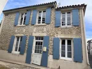 an old brick building with blue shuttered windows at Mais 4 pièces Oléron 6 couchages SAINT GEORGES D'OLERON SGO000-607 in Saint-Georges-dʼOléron