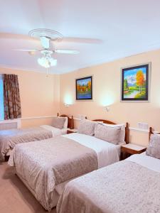 une chambre d'hôtel avec trois lits et un plafond dans l'établissement Europa House Hotel, London Paddington, à Londres