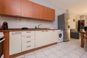 a kitchen with white cabinets and a refrigerator at Jella's sunny apartment in Nea Skioni