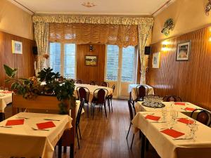 a restaurant with white tables and chairs and a window at Hôtel Restaurant Les Arcades in Limoux