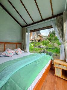 a bed in a room with a large window at Satha private villa Dieng 3 in Banjarnegara