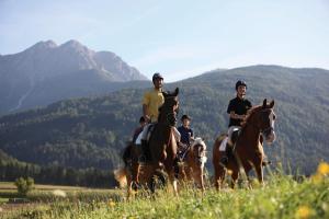a group of people riding horses in a field at Hotel Garni Lichtenau in Schenna