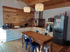 a kitchen with a wooden table and a refrigerator at La forestière avec Jacuzzi pour 6 personnes in Saint-Georges-dʼOléron