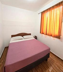 a bedroom with a bed with a purple blanket and a window at Hostal Las Cruces in Arica