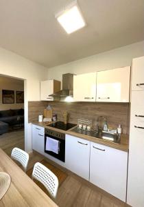 a kitchen with white cabinets and a sink and a stove at Gemütliche 2 Zimmer Wohnung nahe Köln am Hürth Park in Hürth