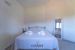 1 dormitorio con 1 cama con sábanas blancas y toallas en Mare & Tranquillità - Trilocale con Wi-Fi, en Olbia