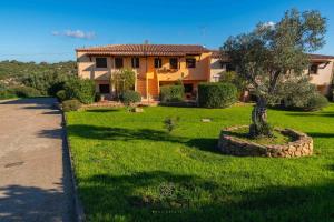 una casa con un patio verde delante de ella en Mare & Tranquillità - Trilocale con Wi-Fi, en Olbia