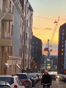 a woman riding a bike down a street with cars at "Studio Miami", Helsinki city center in Helsinki