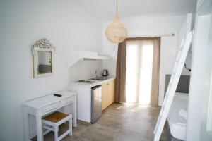 a white kitchen with a sink and a table at Casa di Flora in Loutra +17 photos