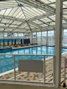 a large swimming pool with blue water in a building at Duffy's Den - Parkdean California Cliffs - Fulmar 45 in Scratby