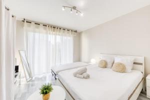 a white bedroom with two beds and a window at Grand studio proche Disney / Val d'Europe in Lagny +3 photos