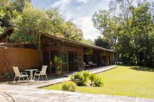 a house with a patio and a table and chairs at Pousada Sete Sinos in Itaipava