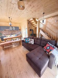 ein Wohnzimmer mit einem braunen Sofa und einer Treppe in der Unterkunft Domek Sol Wilcza Zagroda in Kudowa-Zdrój + 19 Fotos