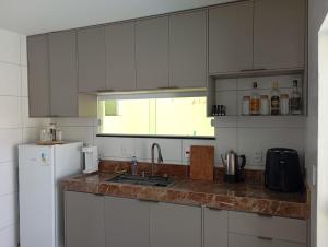 a kitchen with white cabinets and a sink and a refrigerator at Casa confortável in Arembepe in Camaçari