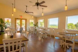 a dining room with tables and chairs and windows at Whispering Woods Cabins & Grill in Jordan