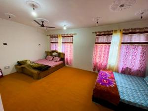 a bedroom with two beds and a couch and windows at Adeel Homes in Srinagar