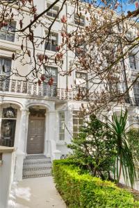 a white house with a balcony and stairs at Grove Heights Notting Hill in London