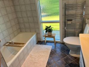 a bathroom with a tub and a toilet and a plant at House close to city center, beach and Great Northern in Kerteminde +17 photos