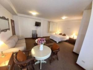 a hotel room with a bed and a table with flowers at Hotel Incasol Agosto Ejecutivo Matrimonial Individual Suite Desayuno Incasol Tranporte y Cochera Gratis in Ayacucho