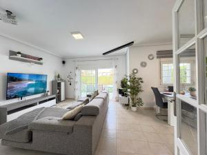 a living room with a couch and a flat screen tv at Villa Sofía - 2 bedroom villa with private pool and garden in Baños y Mendigo