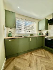 a kitchen with green cabinets and a sink at Cozy Cottage Retreat in Portsoy