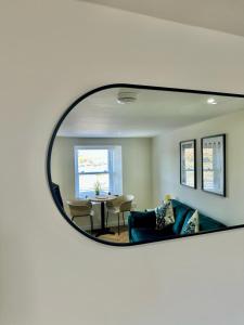 a mirror reflecting a living room with a couch and a table at Cozy Cottage Retreat in Portsoy
