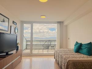 a bedroom with a bed and a television and a balcony at Gray Fox Apartments - Deloqui in Ushuaia