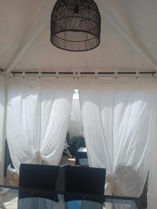 a tent with white curtains and a glass table at Villa Lucia in Lampedusa