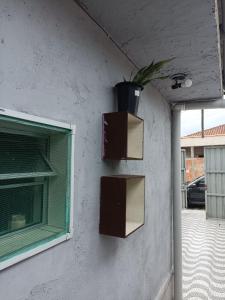a wall with two boxes and a potted plant on it at Casa Praia Mongaguá in Mongaguá