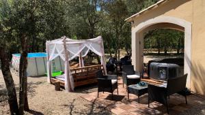 a gazebo with a tent and chairs and a grill at gite le repos des chênes option spa extérieur Evasion nature et confort ! in Régusse