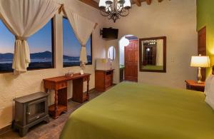 a bedroom with a green bed and a desk and window at Eco Hotel Ixhi in Pátzcuaro