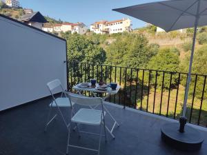 a table and chairs on a balcony with an umbrella at Casa do Cabecinho in Pampilhosa da Serra