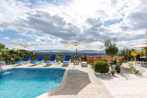 a pool with chairs and umbrellas on a patio at Dream Villa in Tala with Private Pool, Sea & Mountain Views & Garden Retreat in Paphos City