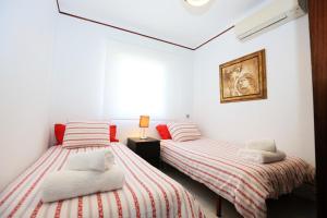 two beds in a white room with red and white stripes at La Torre - Villa Rosamar Beach in Cambrils