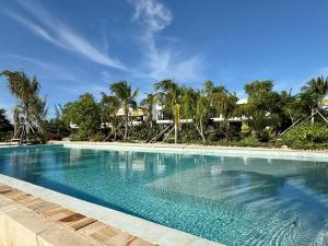 a swimming pool with blue water and palm trees at Palmera Zanzibar Eco Boutique Hotel in Dimbani