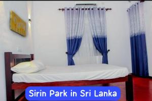 a bed in a room with blue curtains at Sirin Park Eco Tour in Horagampitiya
