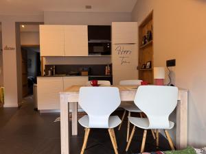 eine Küche mit einem Holztisch und weißen Stühlen in der Unterkunft New Ski Apt in Three Valleys - L'Écrin in Brides-les-Bains