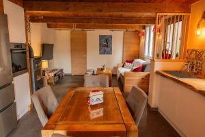 a kitchen and living room with a wooden table and chairs at Maison au cœur du village de saint Étienne de tinée in Saint-Étienne-de-Tinée +5 photos